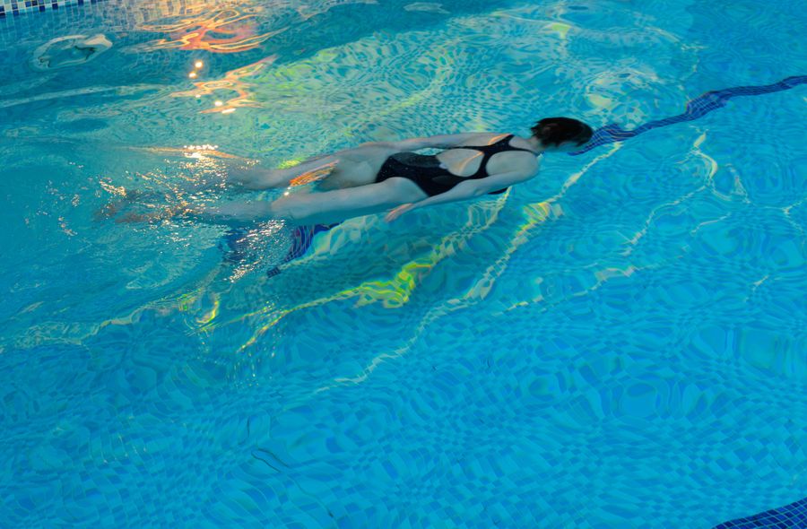 A swimmer crossing the indoor pool, light moving on the water