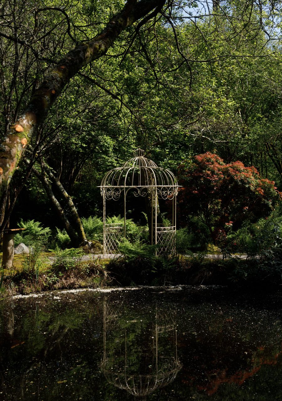 The wrought-iron birdcage gazebo on the pond, reflected in still water